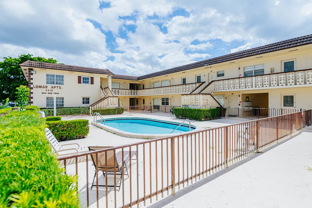 a swimming pool in front of a building with a resort style pool