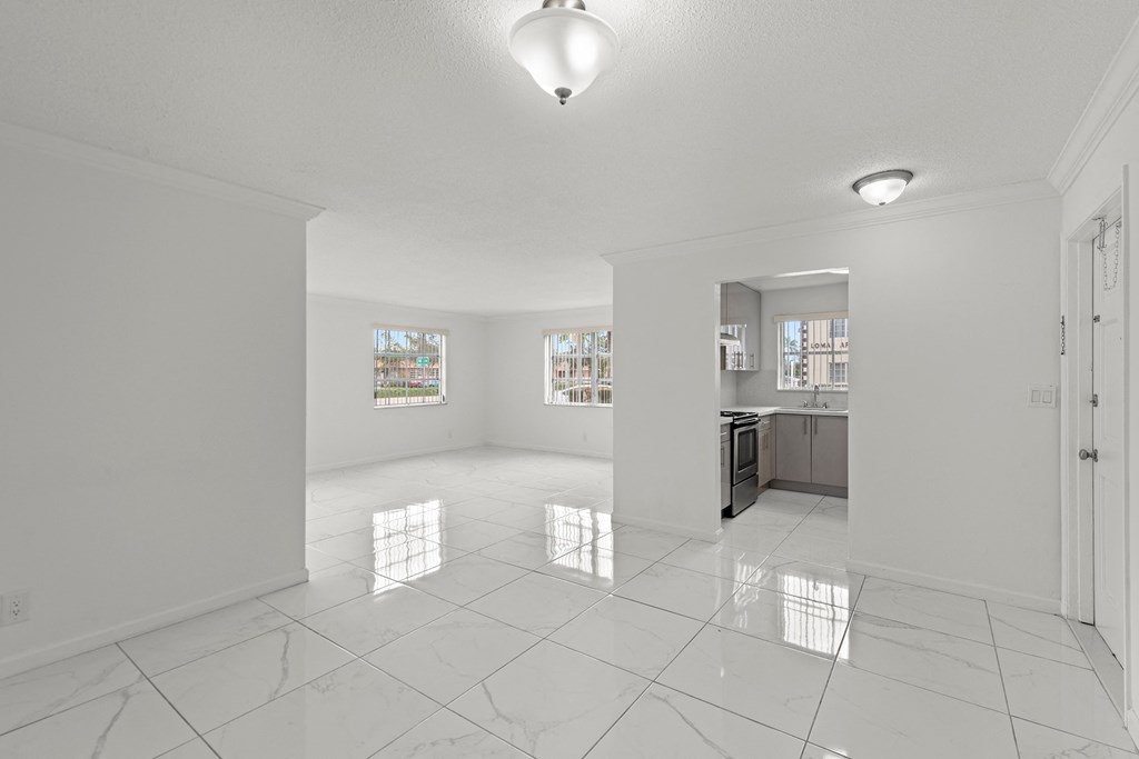 the living room and kitchen of a new home with white walls and tiled floors