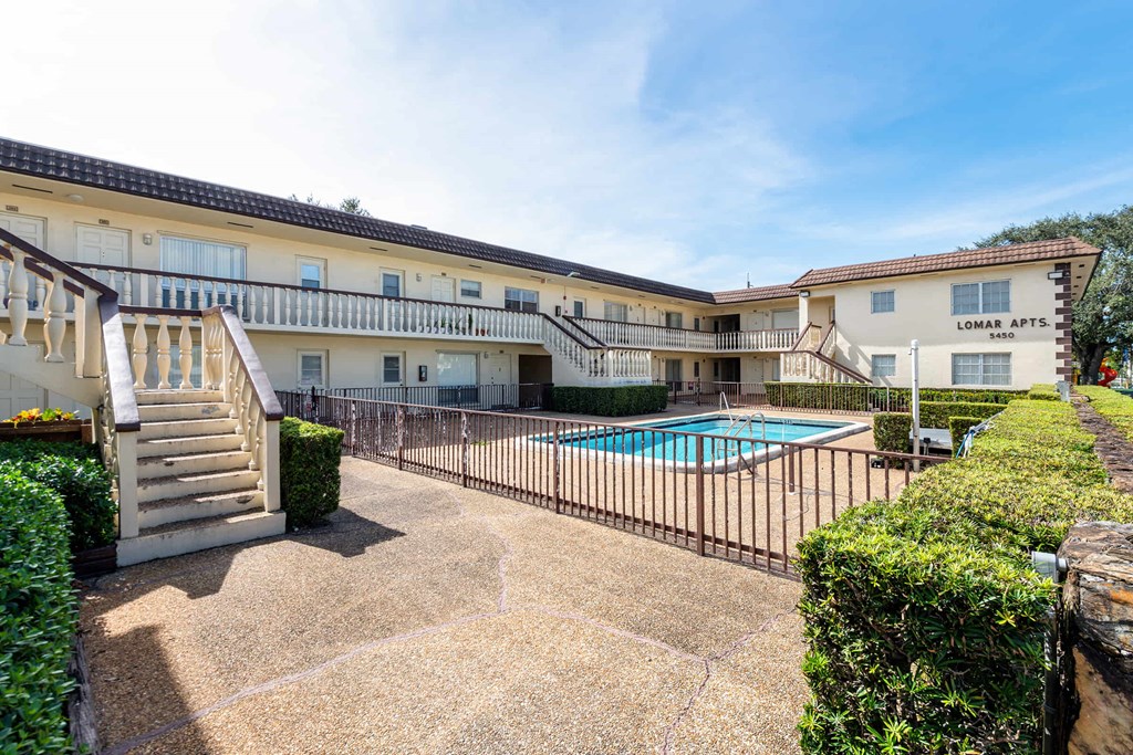 a courtyard with a pool and a building with a fence