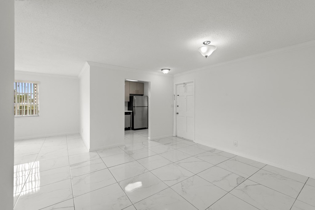 the living room and kitchen in a new home with white walls and tile flooring
