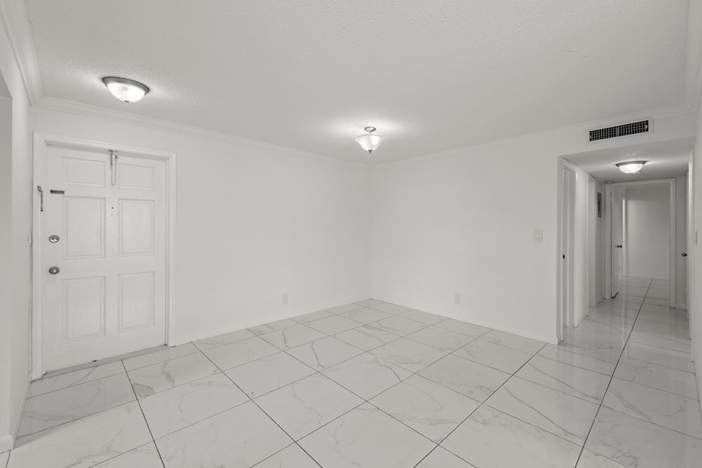 an empty living room and hallway with white walls and tile floors
