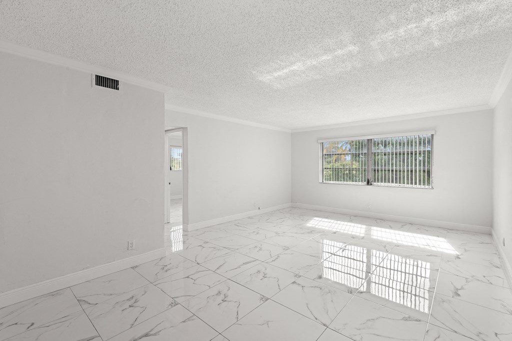 an empty living room with white marble floors and a window