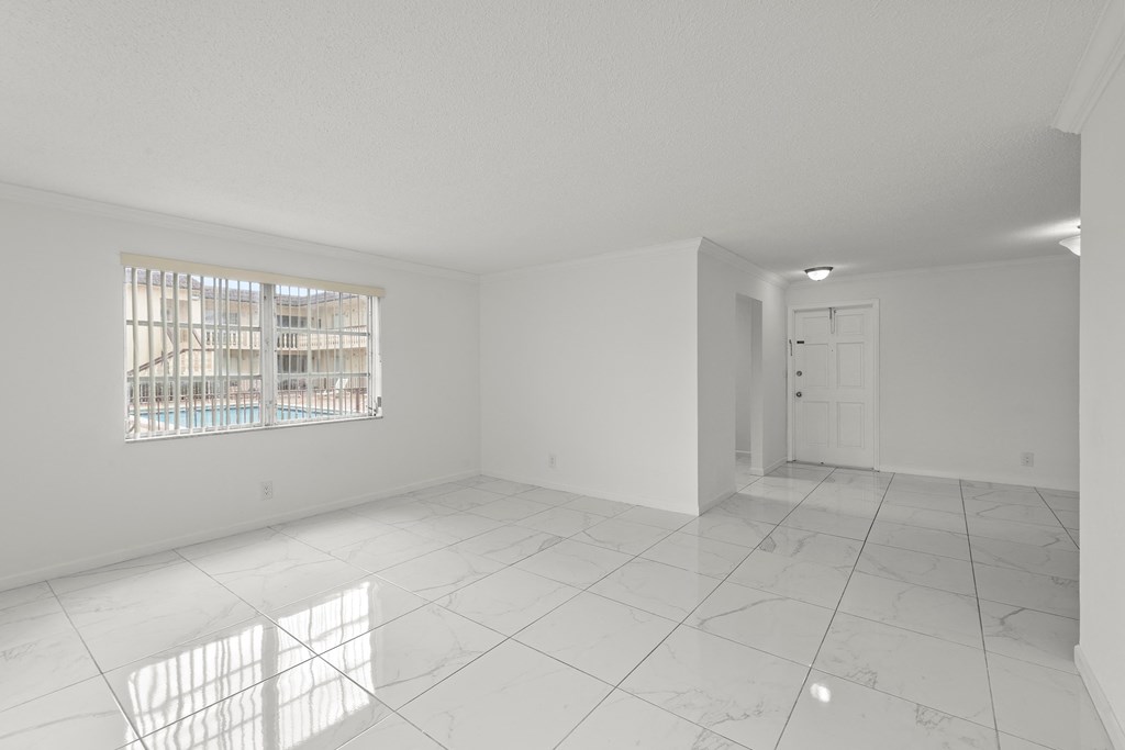 an empty living room with white walls and tile floors
