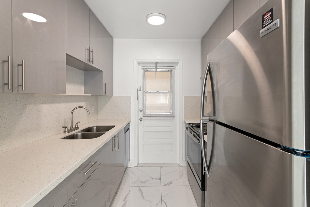 a white kitchen with stainless steel appliances and a sink