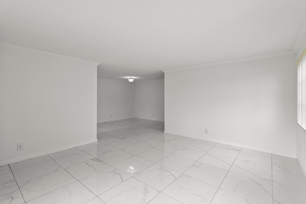 an empty living room with white walls and tile floors