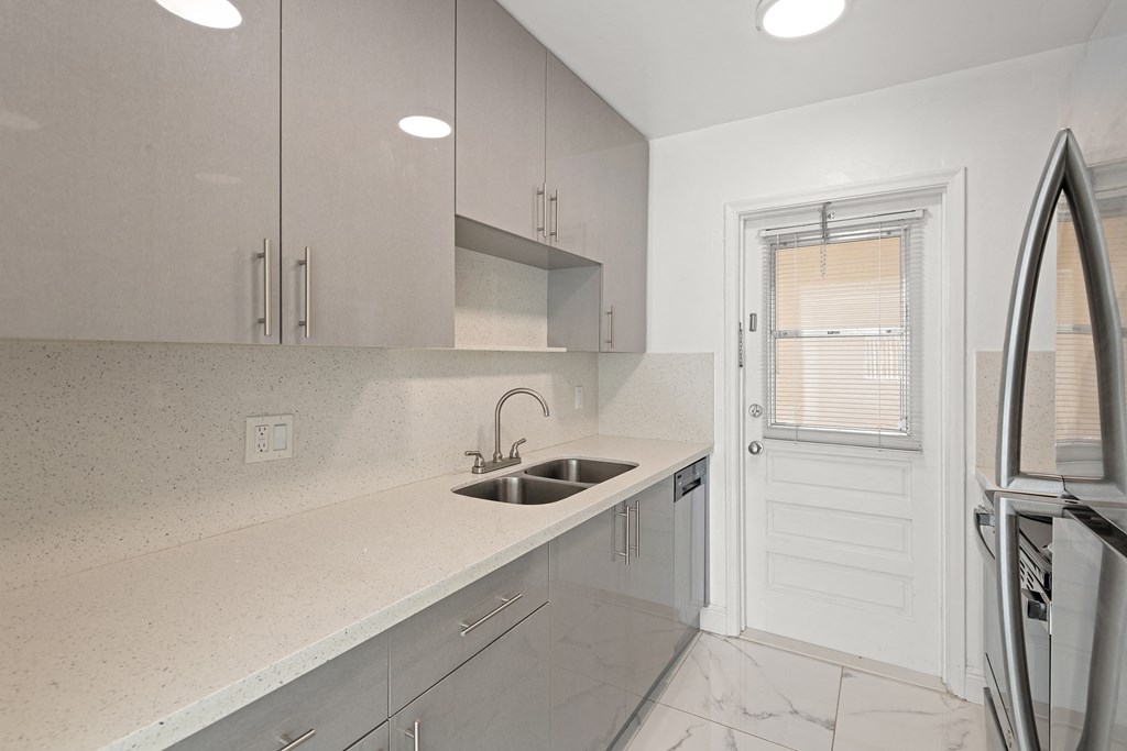 a kitchen with white cabinets and a sink and a door
