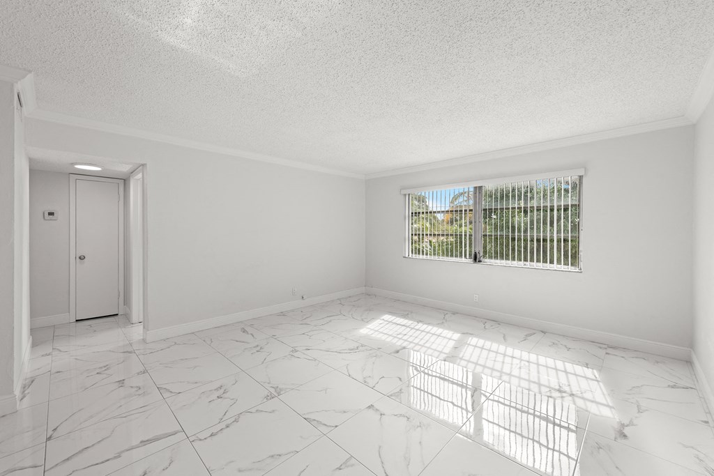 an empty living room with white marble floors and a window