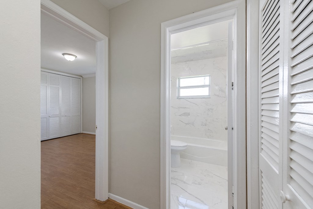 a renovated bathroom with white shutters and a white toilet and shower