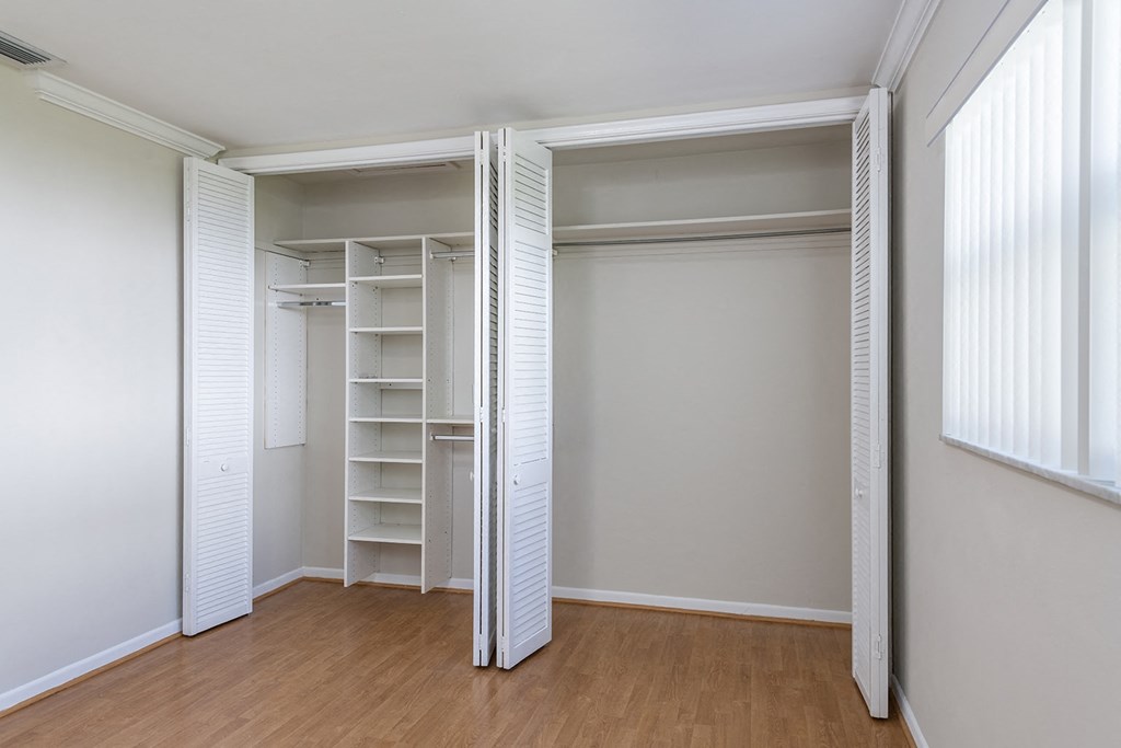 an empty bedroom with a closet with shelves and a wood floor