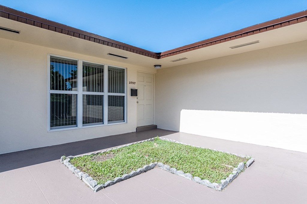 a patio with a patch of grass in front of a house