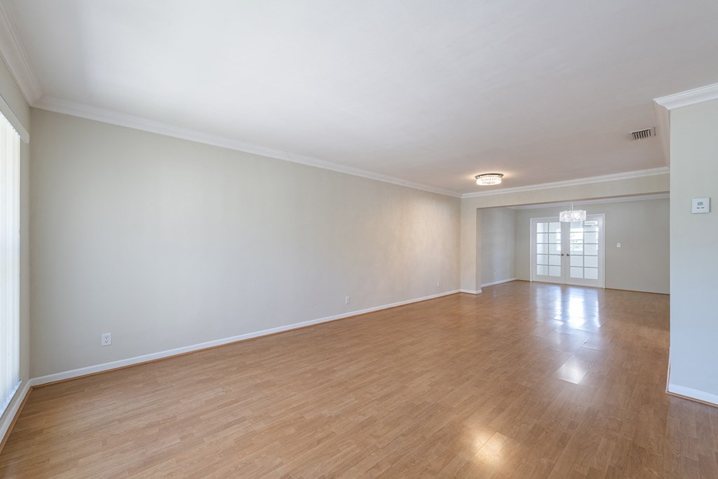 an empty living room with wood floors and white walls