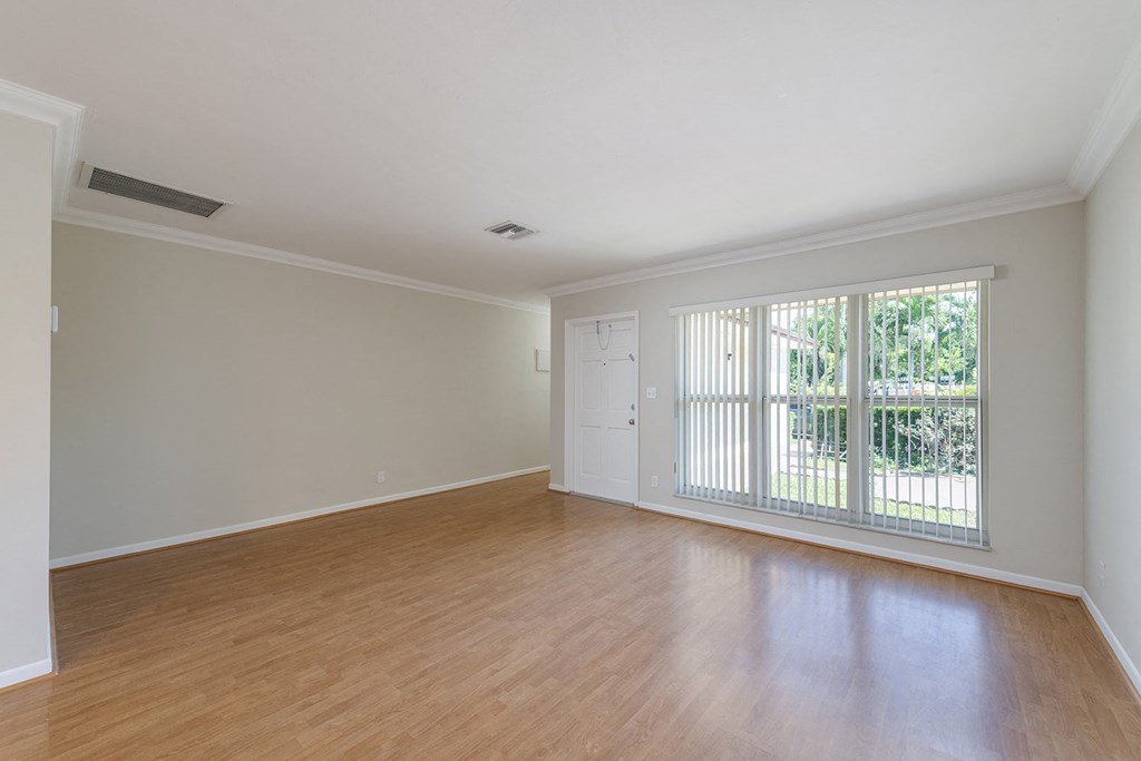 an empty living room with a large window and wood flooring