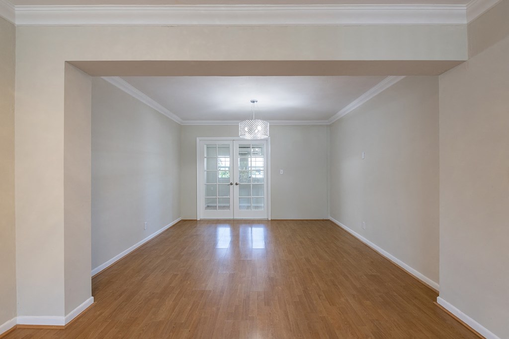 an empty living room with white walls and a wooden floor