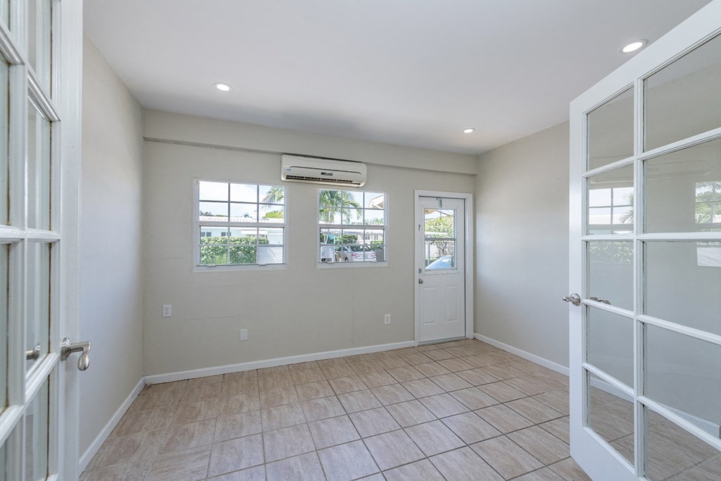 an empty room with doors and windows and a tiled floor