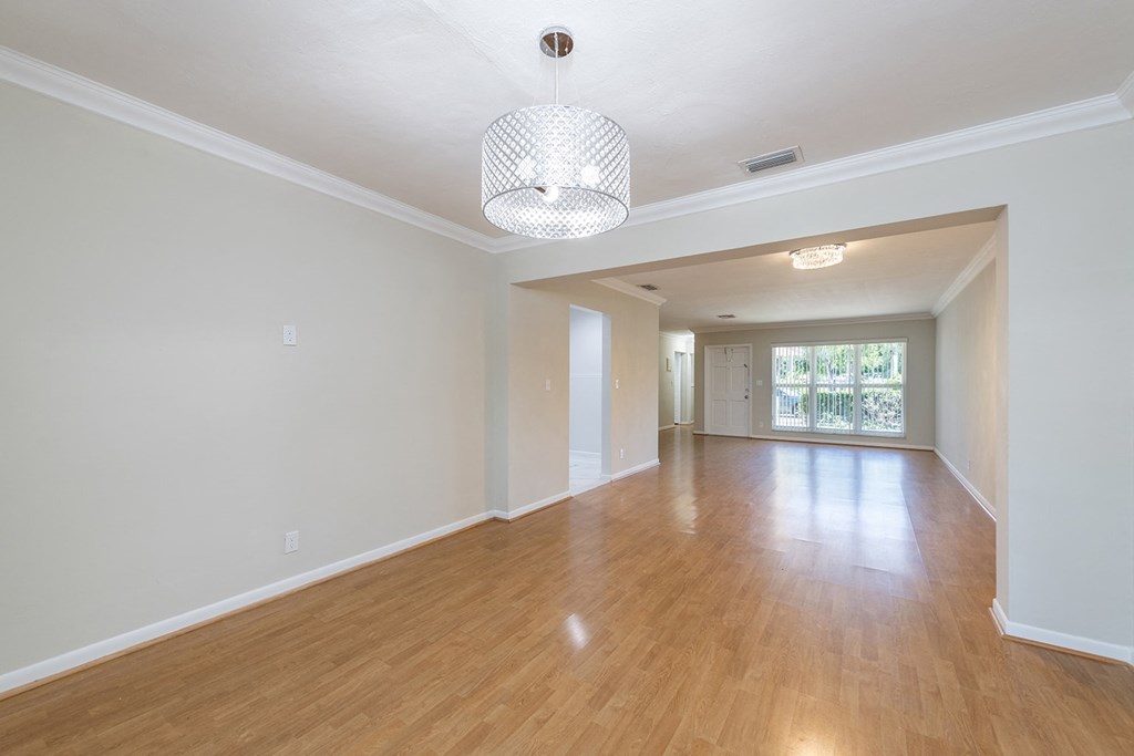 an empty living room and dining room with wood flooring and a large window
