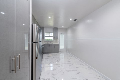 a white and gray kitchen with a refrigerator and a sink