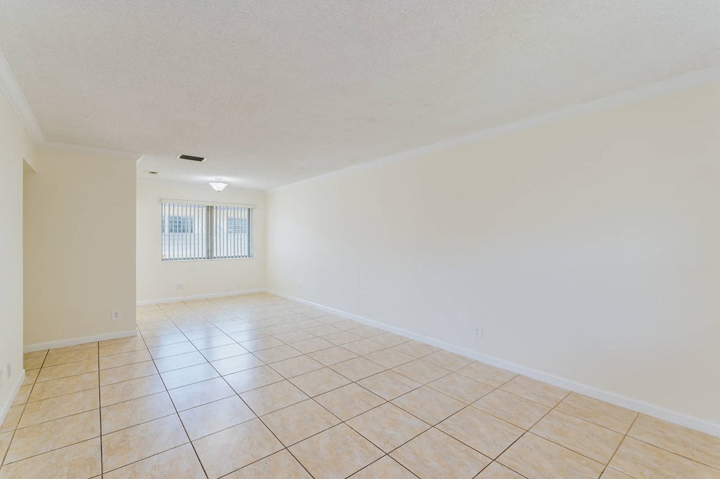 a spacious living room with tile flooring and white walls