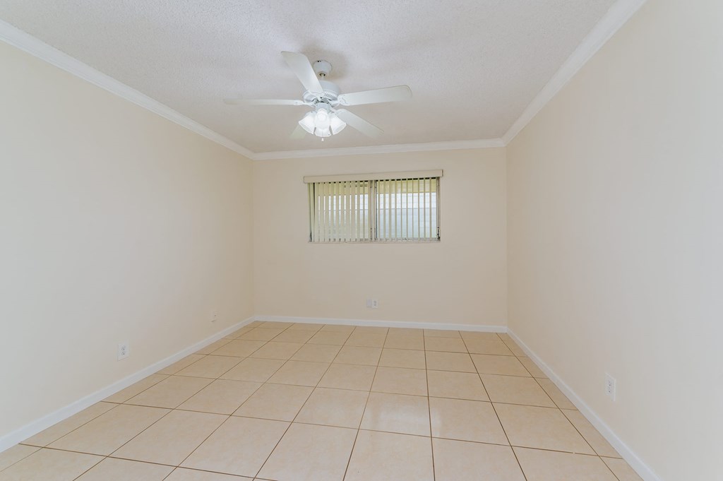 an empty living room with a ceiling fan and a tiled floor