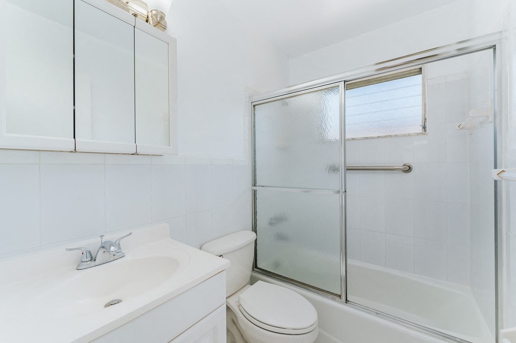 a white bathroom with a shower toilet and sink