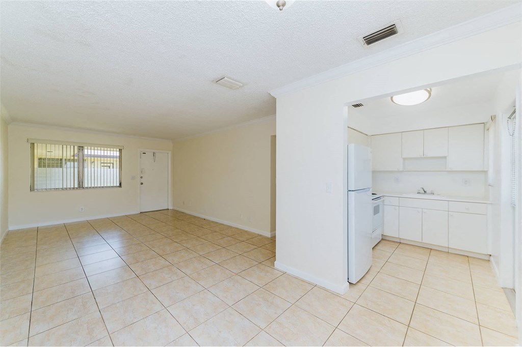 an empty kitchen and living room with a refrigerator and a sink