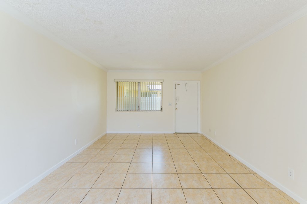 an empty living room with a tiled floor and a white door