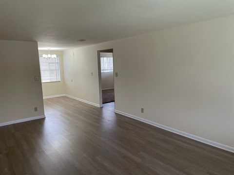 an empty living room with wooden floors and white walls
