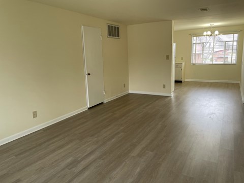 an empty living room with wooden floors and a window