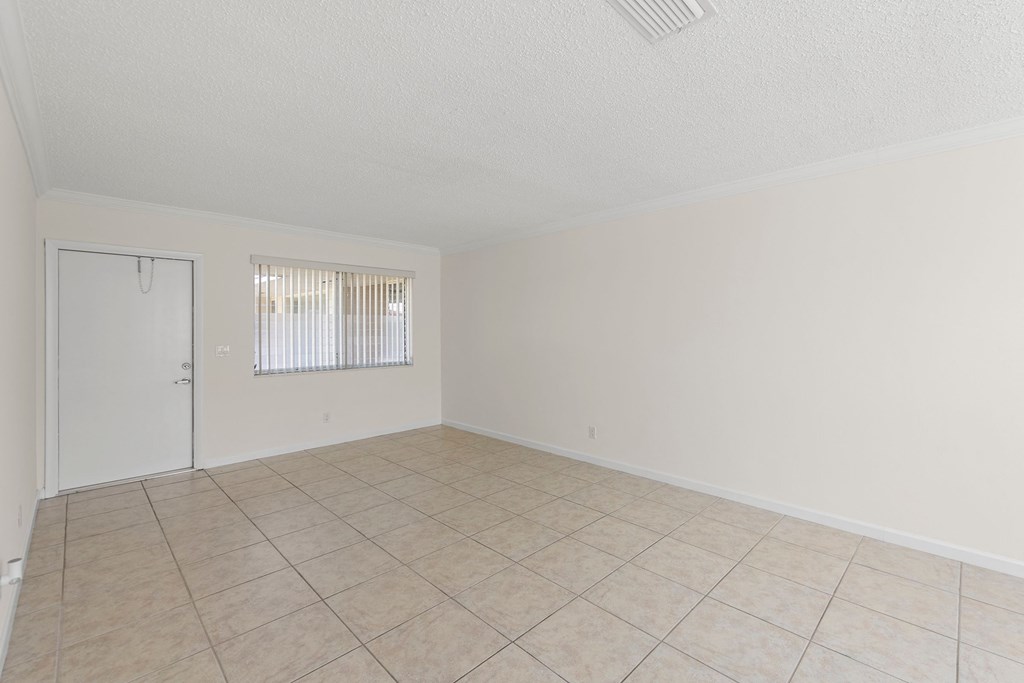 the spacious living room of an empty home with a tiled floor