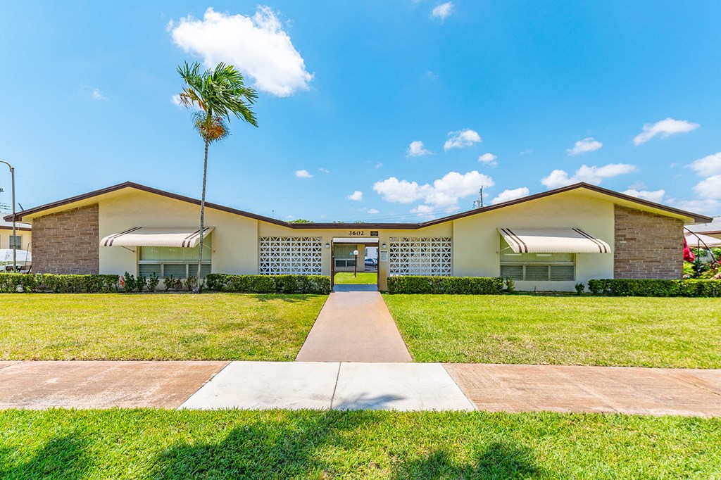 a house with a palm tree and a sidewalk in front of it