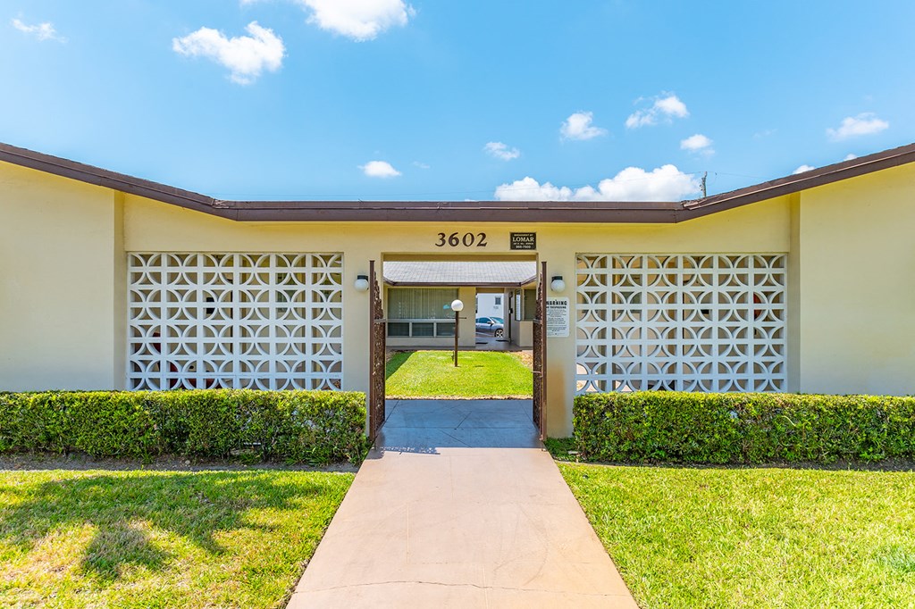 a yellow building with a sidewalk and grass in front of it