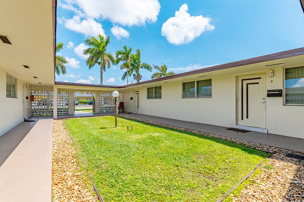 a large white house with a grass yard and palm trees