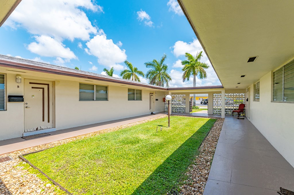 the courtyard of a house with a grass lawn and palm trees