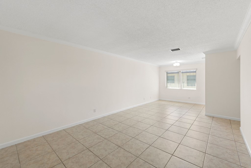 an empty living room with tile flooring and white walls