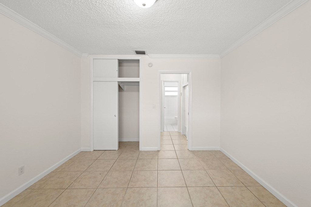 an empty living room with a tile floor and white walls