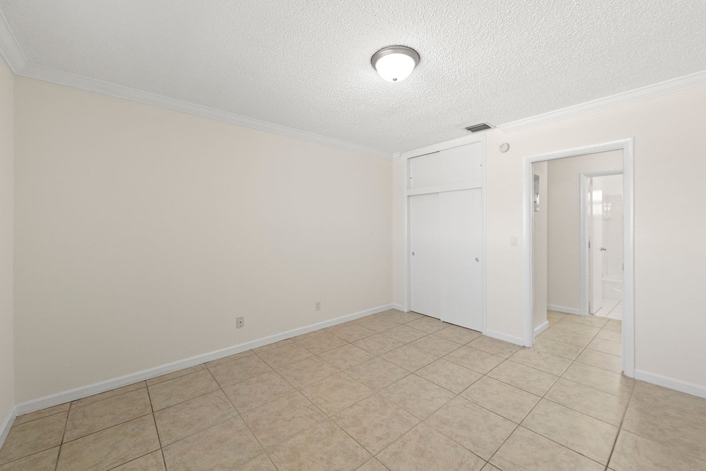 an empty living room with a tile floor and a closet