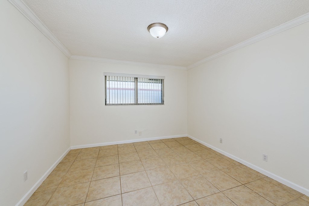 an empty living room with tile flooring and a window