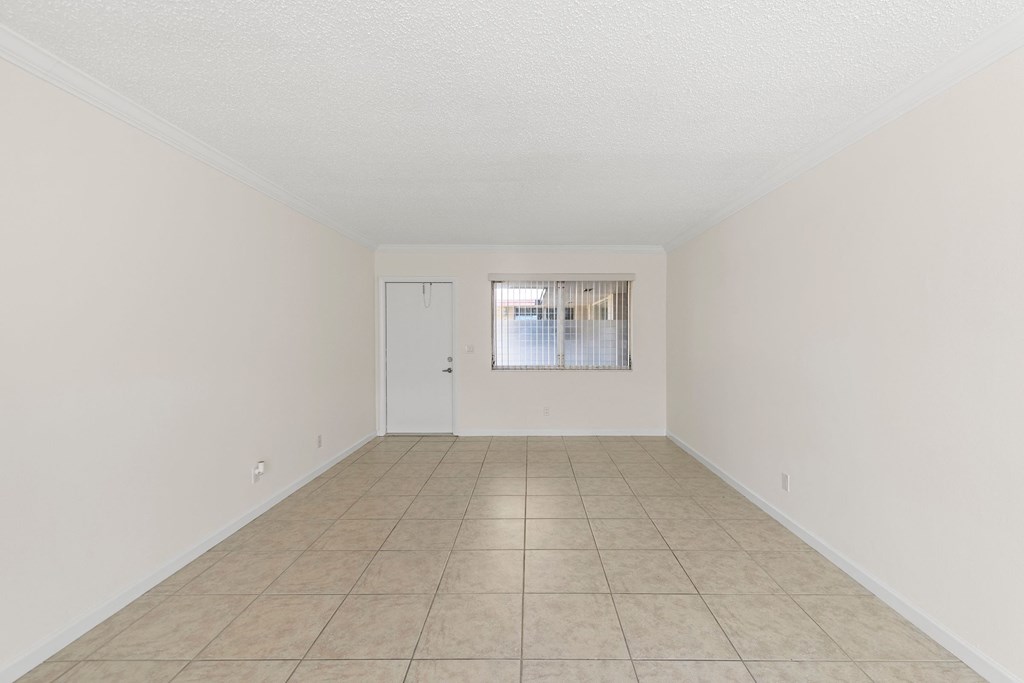 the spacious living room of an empty home with tiled flooring