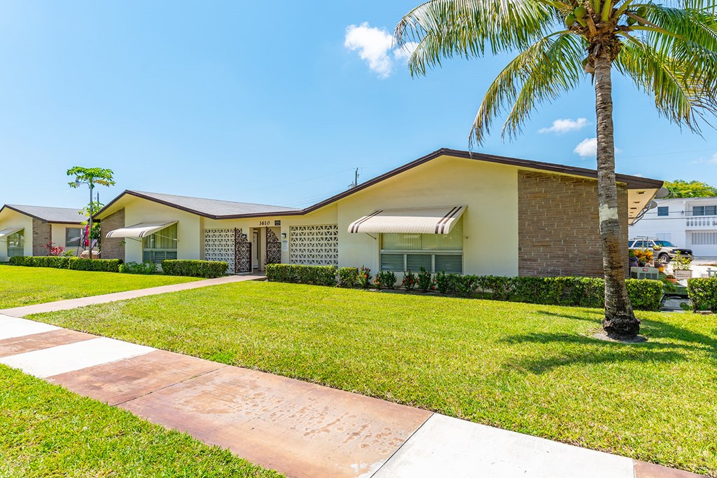 a house with a lawn and palm tree in front of it