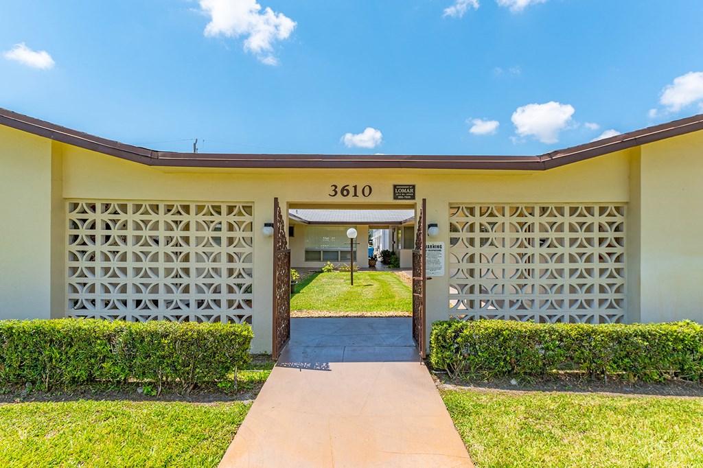 the entrance to a yellow building with a driveway and grass