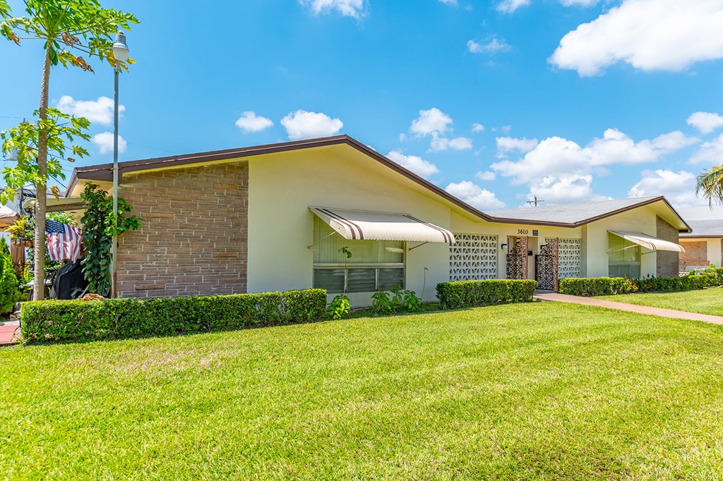 the front of a house with a green lawn and a blue sky