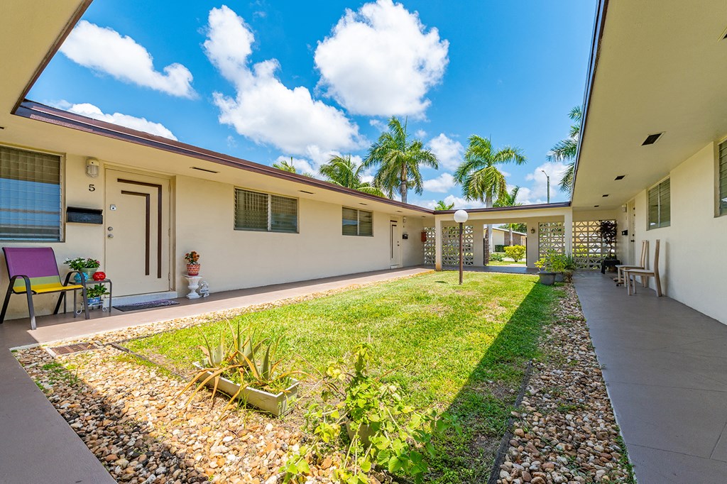a backyard with a lawn and a house with palm trees