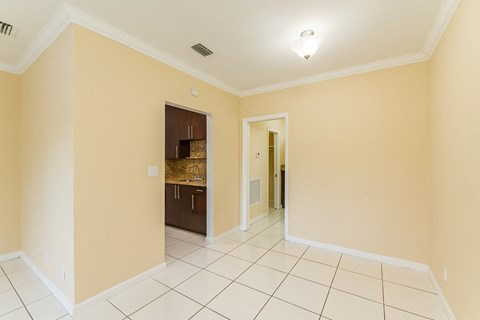 A room with a white tile floor and a doorway leading to another room.