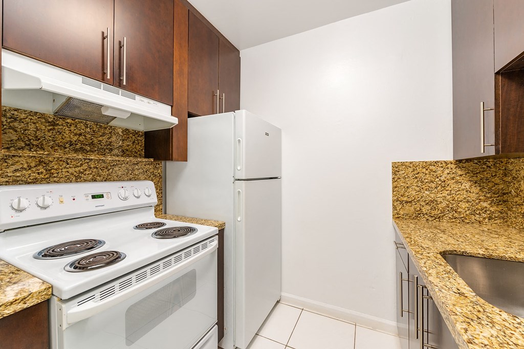 A kitchen with a white stove and a white refrigerator.