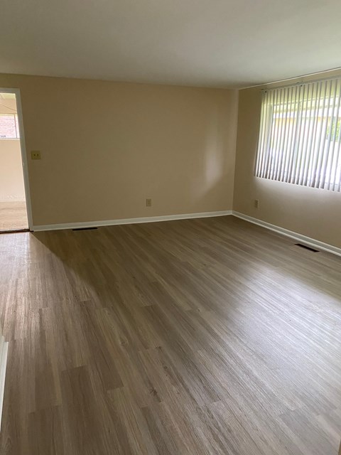 an empty living room with wooden floors and a window