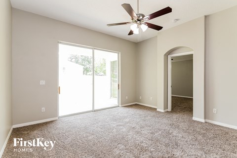 a living room with carpet and a ceiling fan