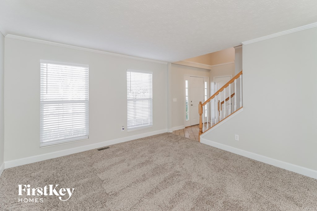 a living room with a carpeted floor and a staircase