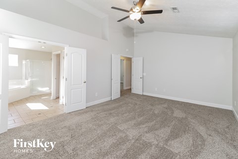 a spacious living room with carpet and a ceiling fan