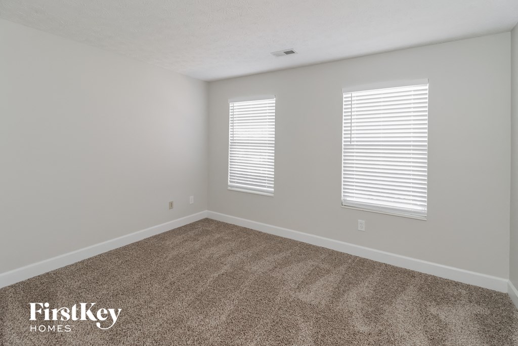 a bedroom with a carpeted floor and two windows