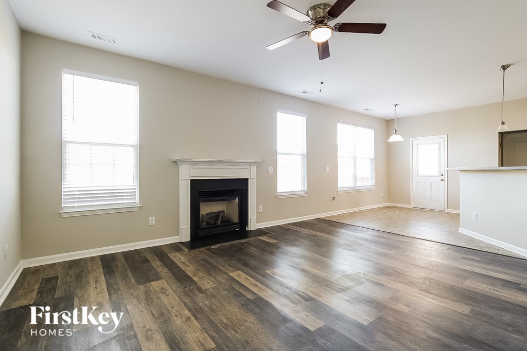 an empty living room with a fireplace and a ceiling fan