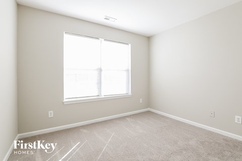 a bedroom with a large window and a carpeted floor